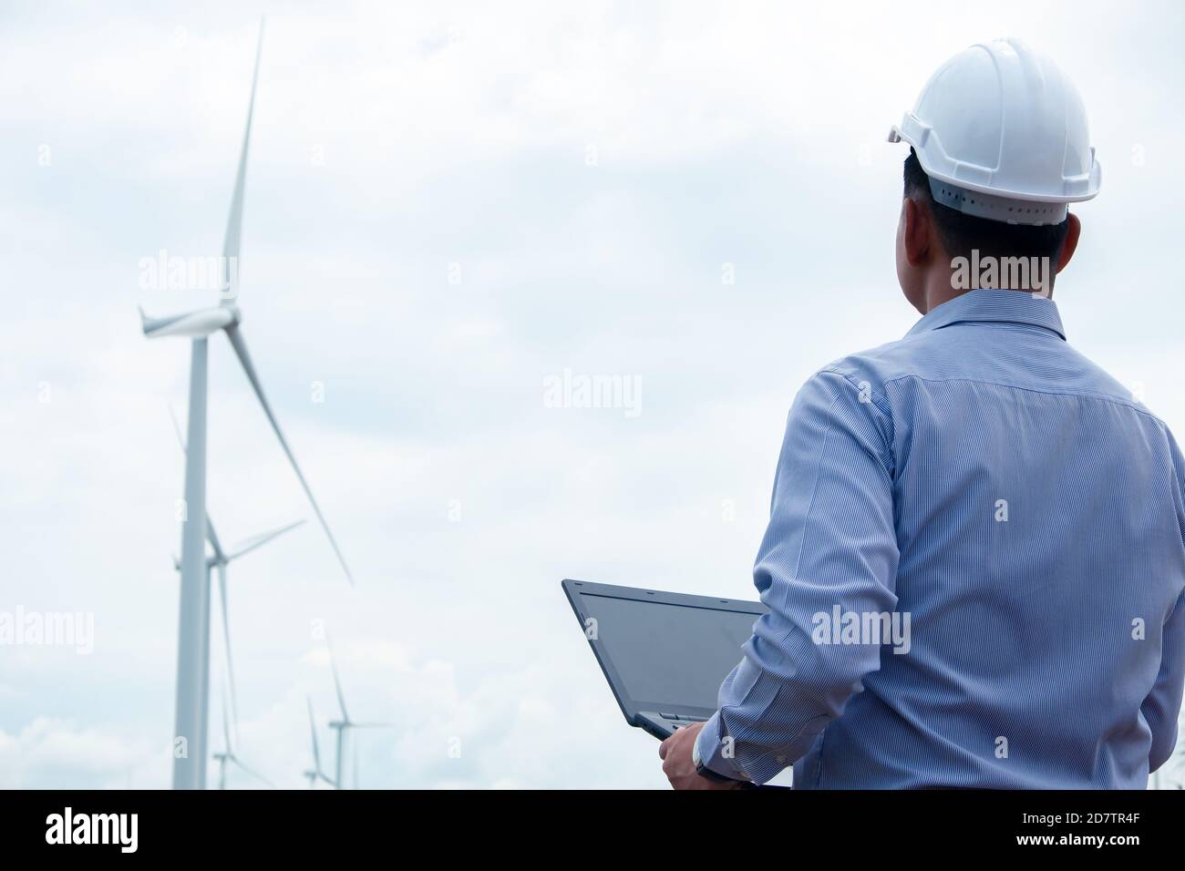 Gli ingegneri mulini a vento stanno lavorando su un computer portatile con la turbina eolica in background Foto Stock
