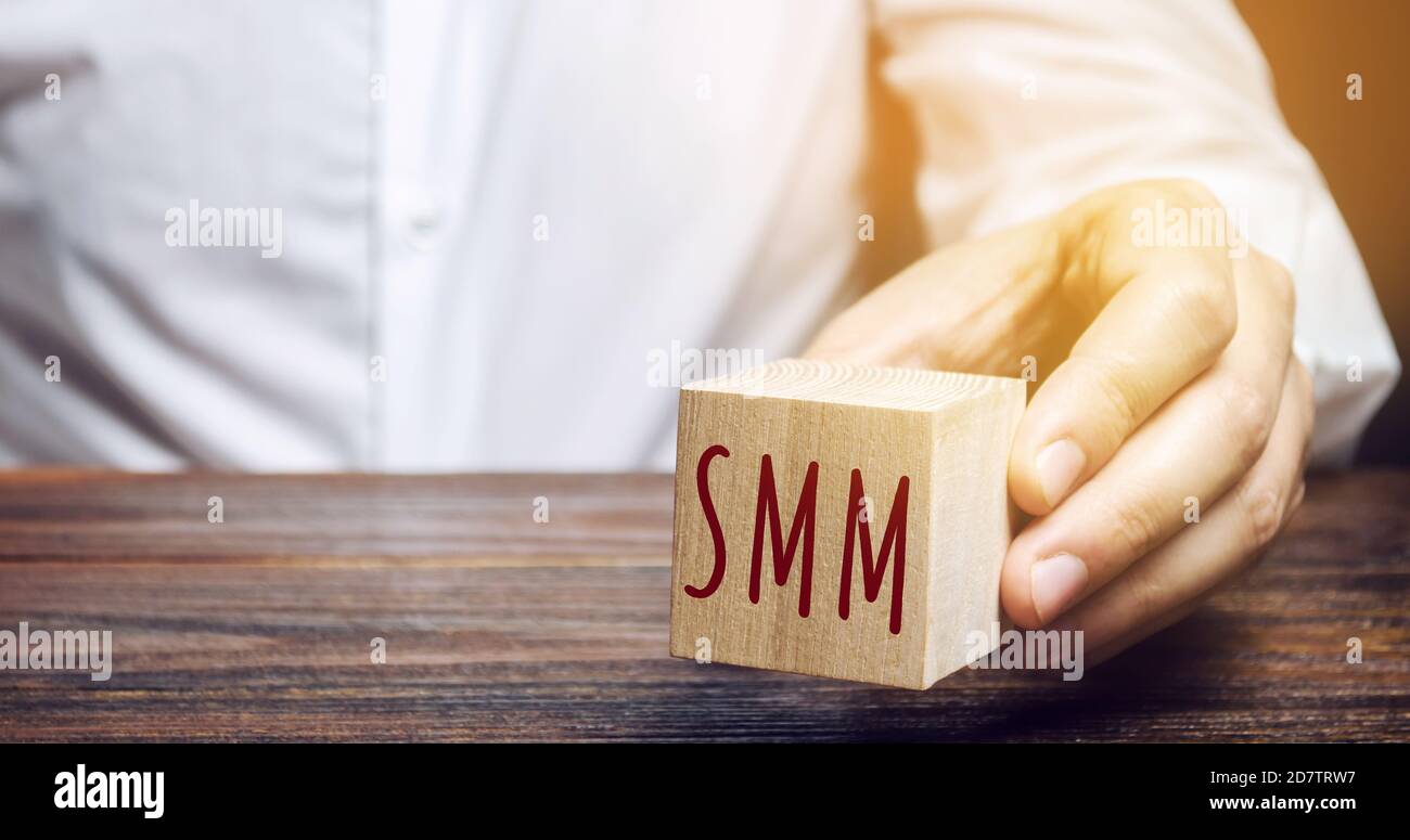 Uomo d'affari che tiene un blocco di legno con la parola SMM. Concetto di Marketing sui social media. Promuovere un prodotto e un servizio. E-marketing, marketing digitale. IO Foto Stock