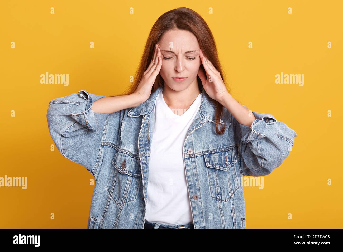 Immagine di infastidita giovane signora turbata che tiene le mani sui templi, che ha mal di testa, che soffre di dolore, che chiude gli occhi, che ha sgradevole expre facciale Foto Stock