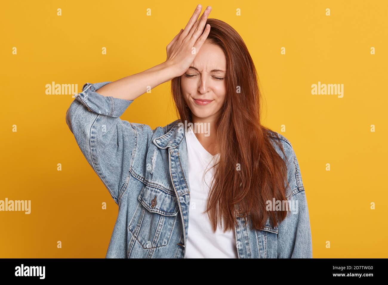 Ripresa interna di giovane attraente donna in standing con occhi chiusi e tiene la mano sulla fronte, ricorda per qualcosa di importante, in posa isolata su y Foto Stock