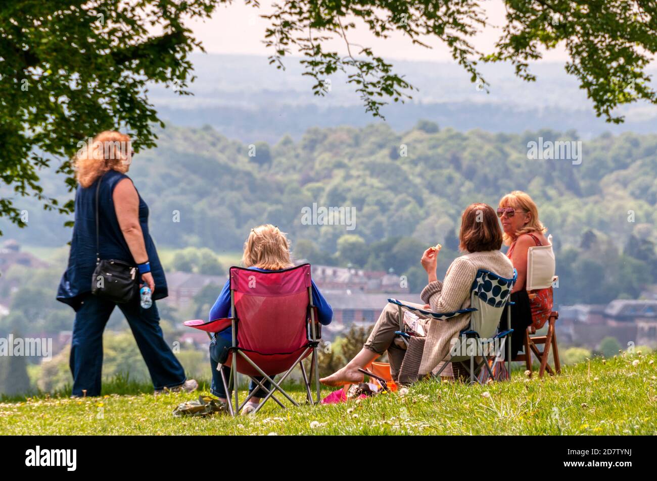 Un gruppo di amici seduti e godendosi la vista su Reigate Hill, Surrey, nella cintura verde di Londra. Foto Stock