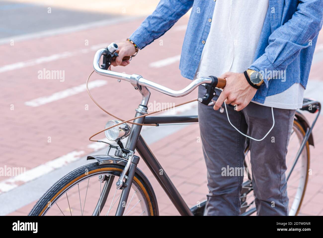 bicicletta urbana in stile retrò tenuta da un giovane irriconoscibile uomo caucasico in abiti casual vicino a un percorso in bicicletta una città Foto Stock