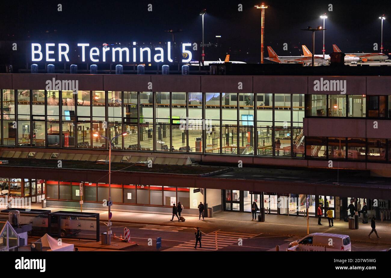 25 ottobre 2020, Brandeburgo, Schönefeld: La nuova scritta "BER Terminal 5" si illumina di sera sul tetto dell'ex aeroporto di Berlino Schönefeld. Agli aeroporti di Berlino viene data la nuova sigla BER. Pochi giorni prima dell'apertura del nuovo aeroporto di capitale, i codici precedenti TXL (Tegel) e SXF (Schoenefeld) non saranno più utilizzati quando l'orario invernale cambia. L'apertura del Capital Airport BER è prevista per il 31.10.2020. Foto: Patrick Pleul/dpa-Zentralbild/dpa Foto Stock