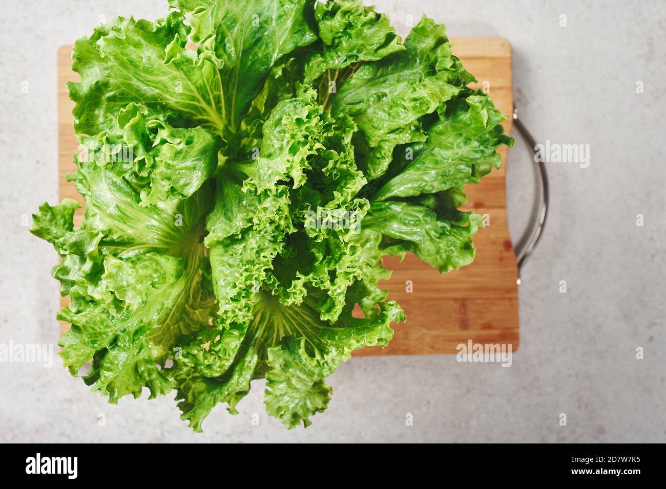 Foglie fresche di lattuga verde sul tavolo da cucina, primo piano. Foto Stock