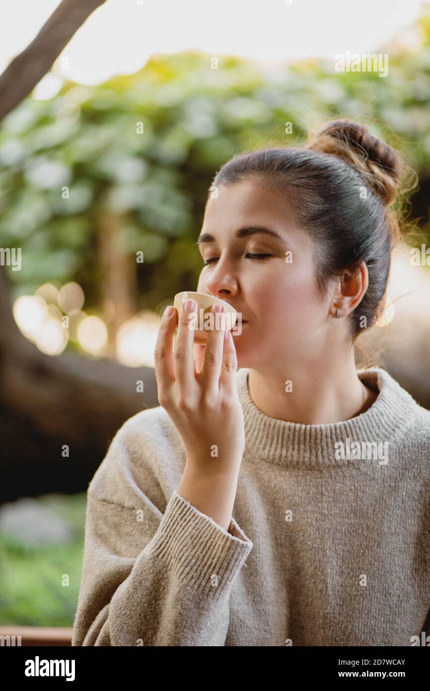 Attraente tè femminile bevuto dalla ciotola all'esterno. Foto Stock