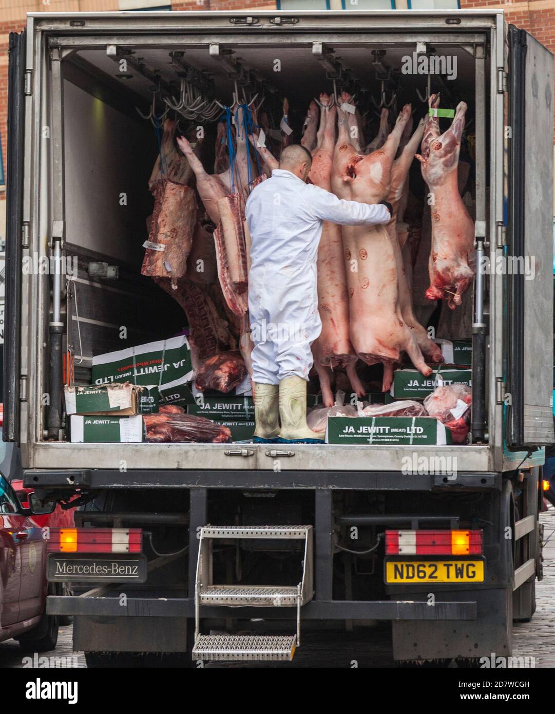 Un uomo che ordina le carcasse di carne sul retro del furgone di consegna della carne in East Row, Darlington, Inghilterra, Regno Unito Foto Stock