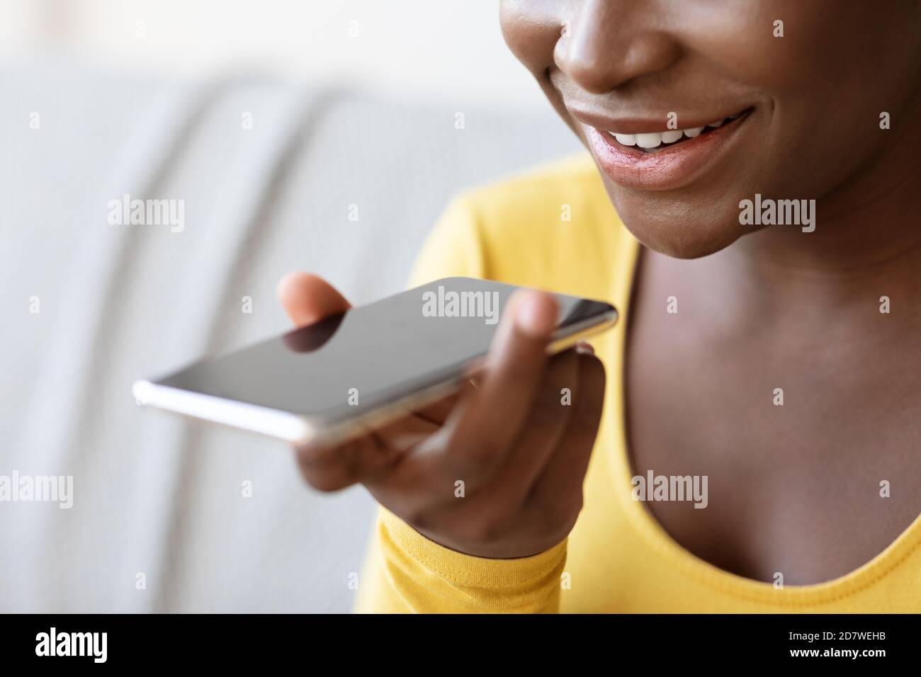 Donna nera con l'opzione Assistente vocale sullo smartphone o registrazione Messaggio audio Foto Stock