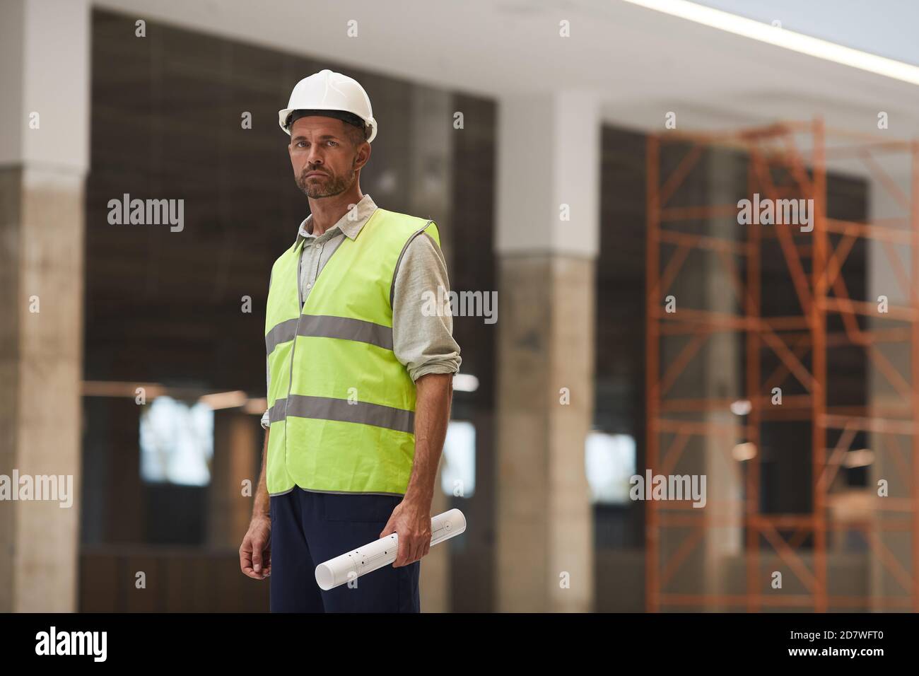 Ritratto di caposquadra maturo che indossa il cappello e guardando la macchina fotografica mentre si trova in cantiere, copia spazio Foto Stock