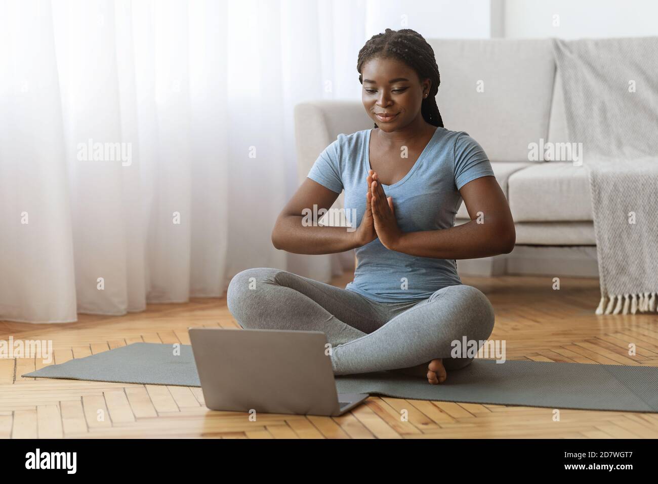 Meditazione online. Black Lady praticare Yoga davanti al laptop a casa Foto Stock