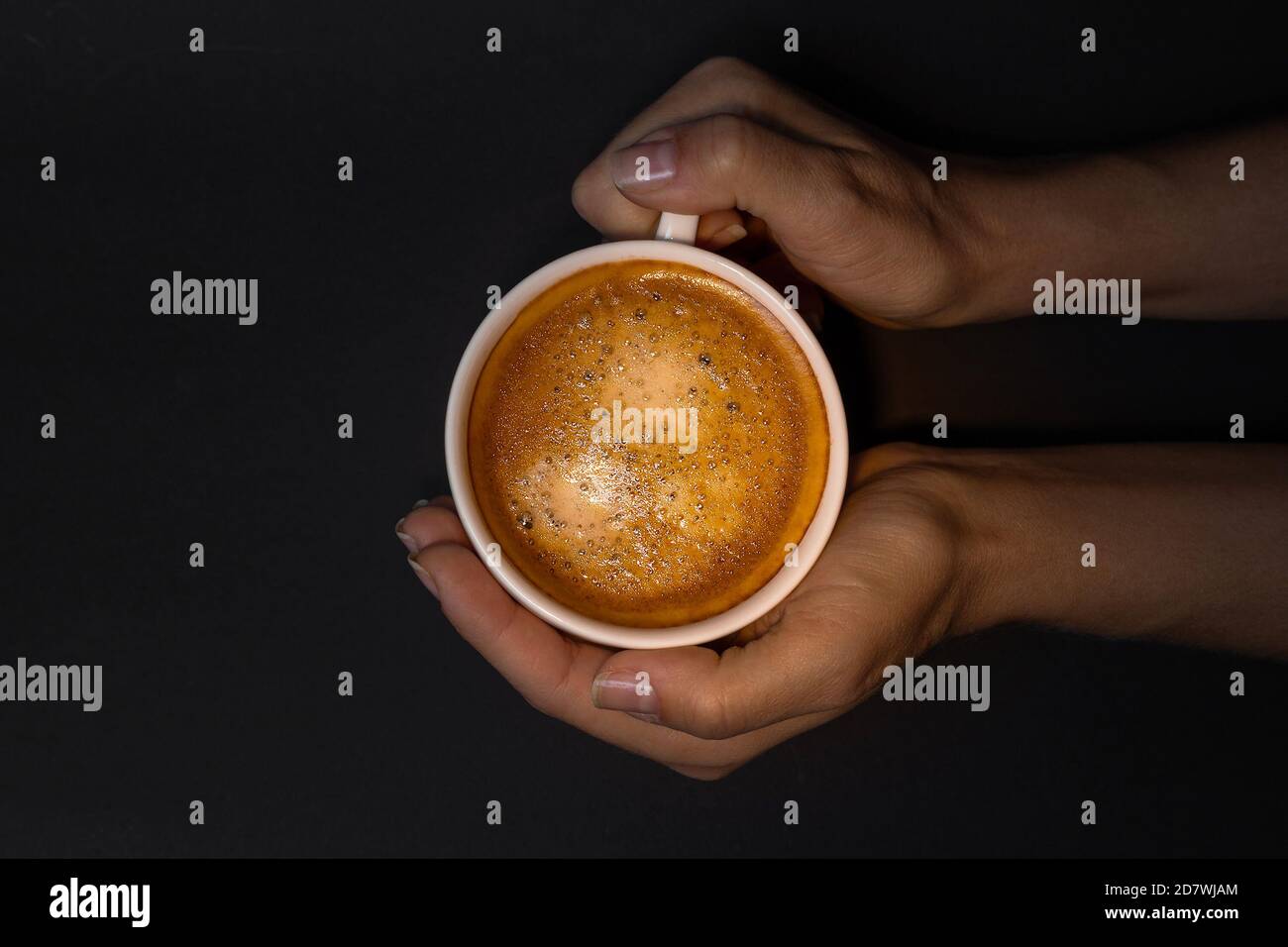 Tazza bianca di caffè con crema in mano. Vista dall'alto Foto Stock