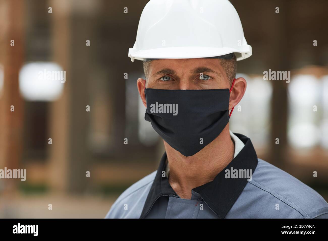 Testa e spalle ritratto di lavoratore maturo indossando maschera e guardando la fotocamera mentre si lavora su un sito industriale, spazio di copia Foto Stock