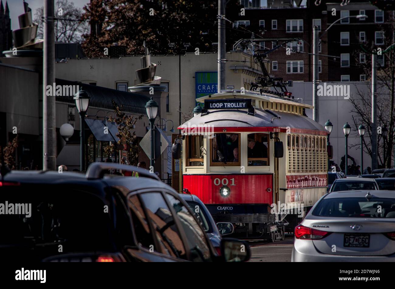 Saint Louis, MO--23 novembre 2018; il tram rosso e giallo per auto d'epoca passa attraverso il quartiere dello shopping della città universitaria su Delmar Blvd. Foto Stock