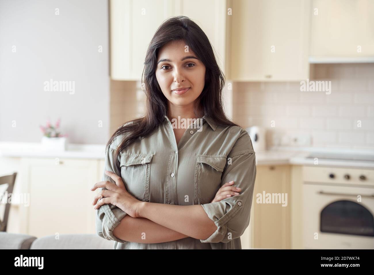 Sorridente giovane indiana guardando la macchina fotografica a casa in cucina, headshot. Foto Stock
