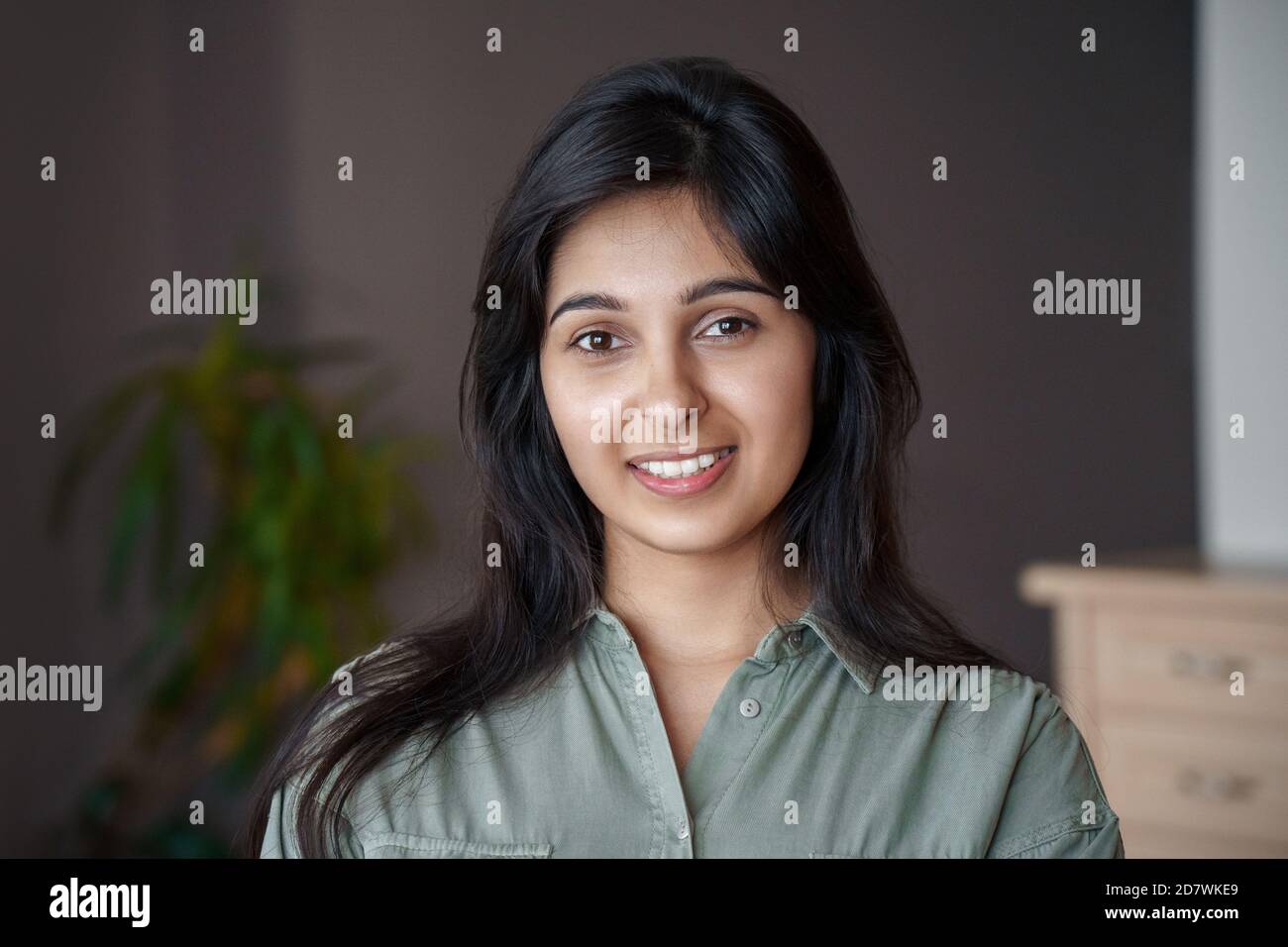 Sorridente giovane signora indiana che guarda la macchina fotografica a casa, ritratto headshot. Foto Stock
