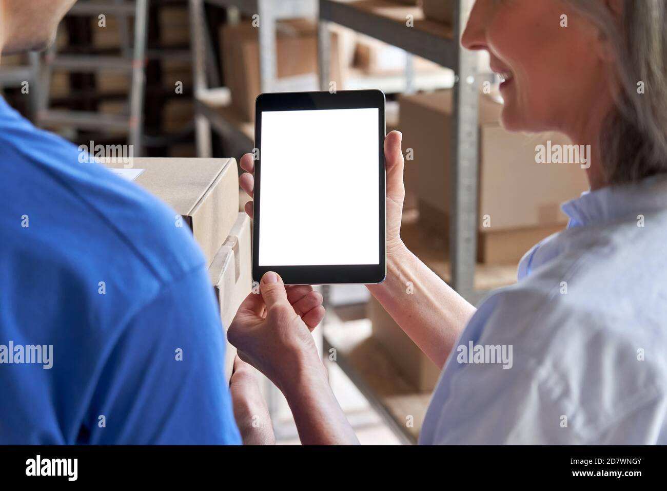 Il responsabile del magazzino dell'inventario che utilizza lo schermo bianco del tablet digitale parla con il corriere. Foto Stock