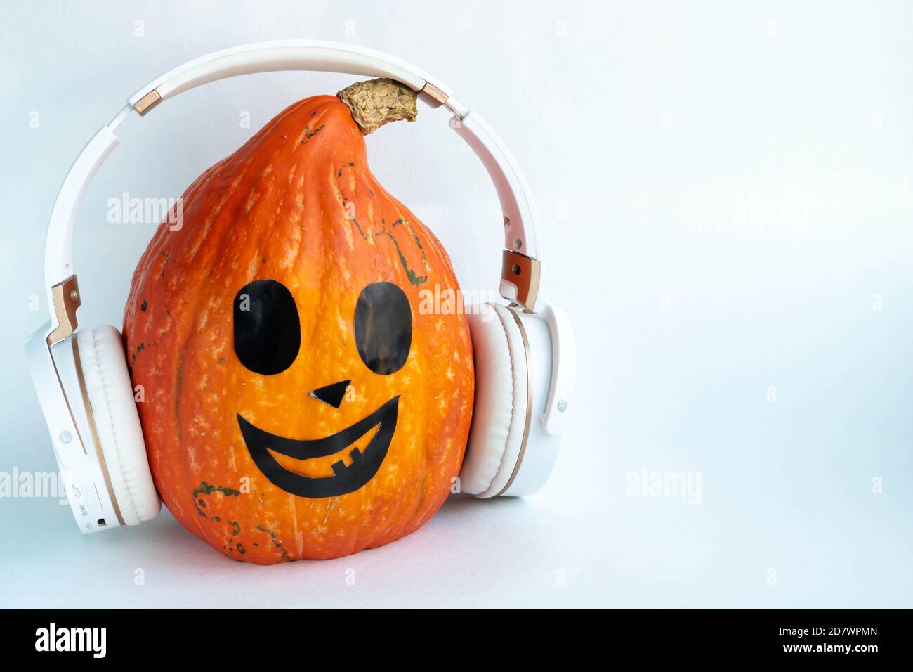Zucca di Halloween con il viso divertente in cuffie.Jack-lanterna ascoltare la musica sulle cuffie. Spazio di copia per il testo Foto Stock