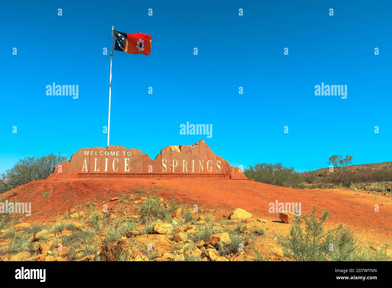 Cartello di benvenuto di Alice Springs e bandiera australiana del territorio del Nord in Australia Centrale. Turismo nel deserto dell'Outback Red Centre. Cielo blu con copia Foto Stock