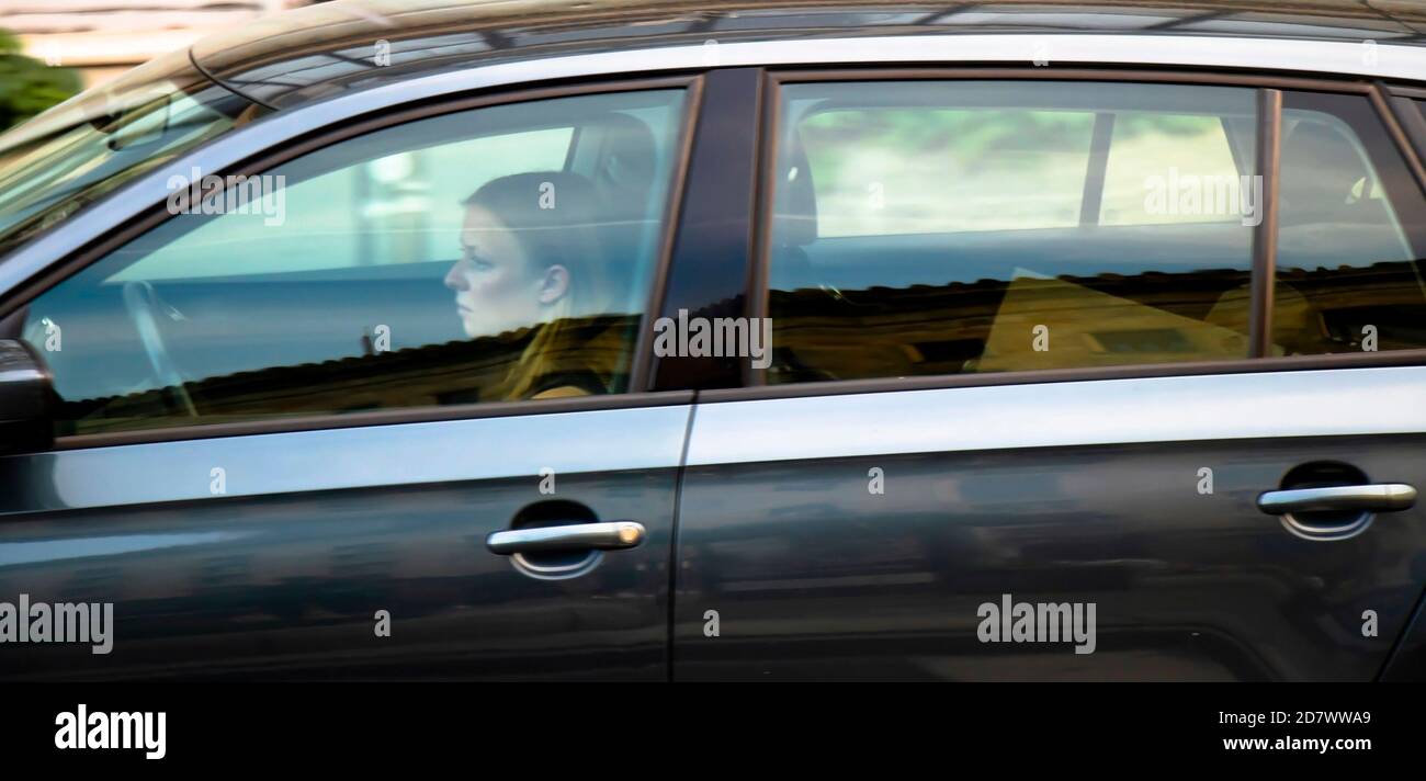 Belgrado, Serbia - 02 ottobre 2020: Giovane donna che guida una macchina, da sola, attraverso una finestra con riflessi e sfocature Foto Stock