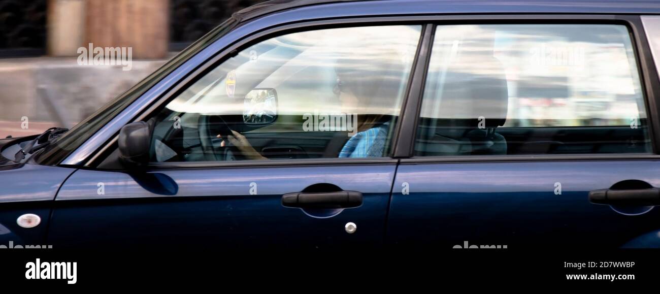 Belgrado, Serbia - 02 ottobre 2020: Donna che guida un'auto sulla strada della città, da sola, attraverso una finestra con riflessi e sfocature Foto Stock