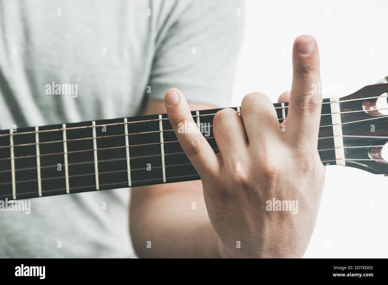 Mano maschio che fa il segno metallico della mano sulla tastiera della chitarra, primo piano Foto Stock
