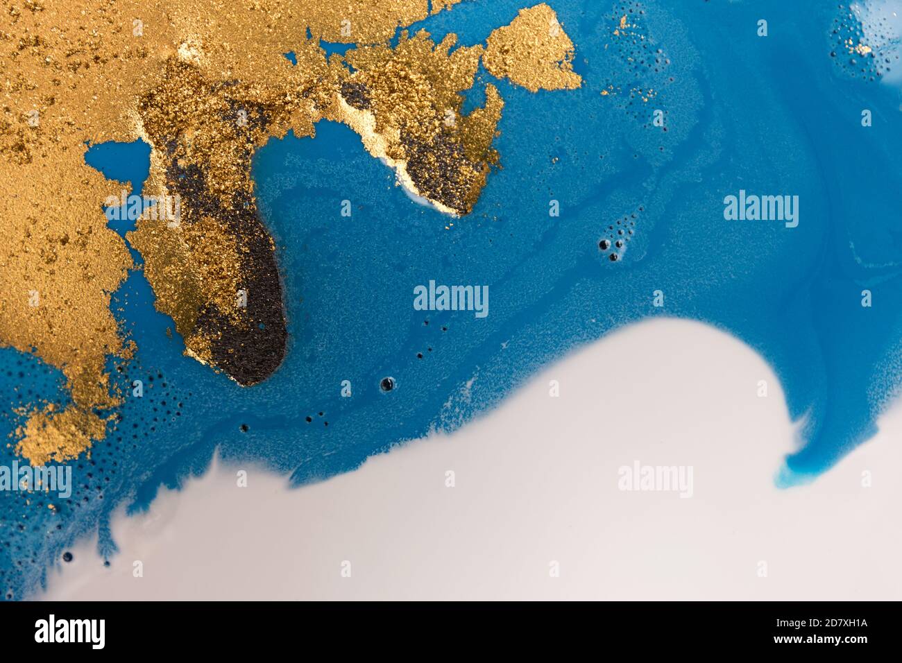 Pile di paillette d'oro su sfondo blu con inchiostro liquido. Modello astratto. Foto Stock