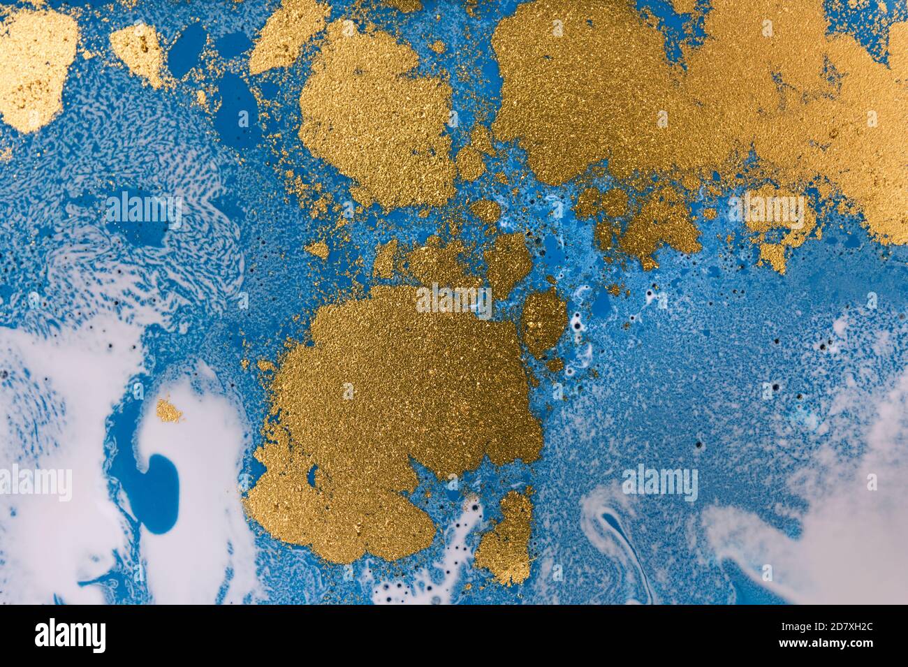 Pile di paillette d'oro su sfondo blu con inchiostro liquido. Modello astratto. Foto Stock