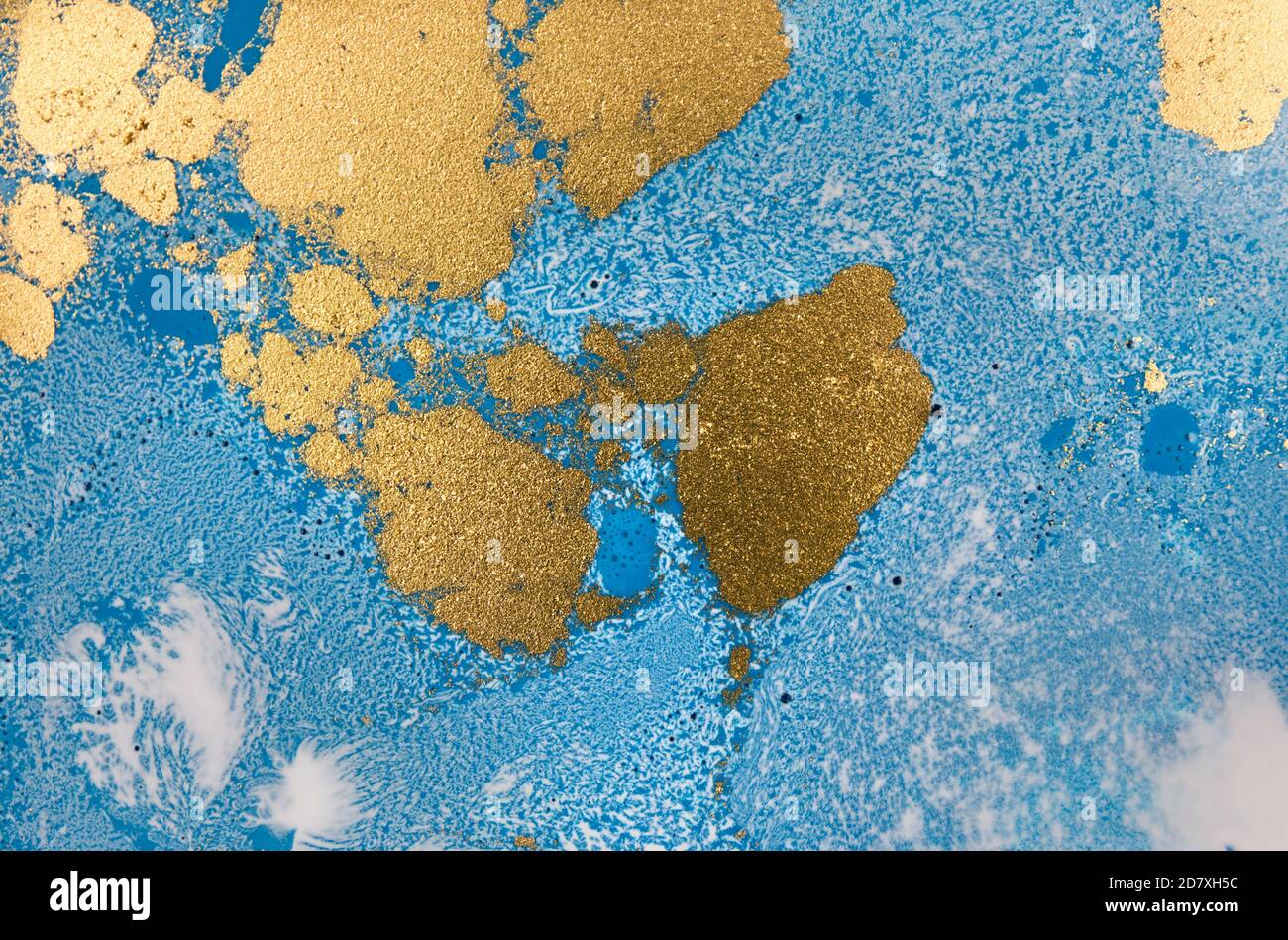 Pile di paillette d'oro su sfondo blu con inchiostro liquido. Modello astratto. Foto Stock