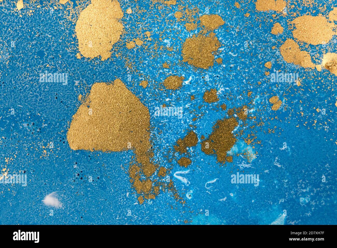 Pile di paillette d'oro su sfondo blu con inchiostro liquido. Modello astratto. Foto Stock