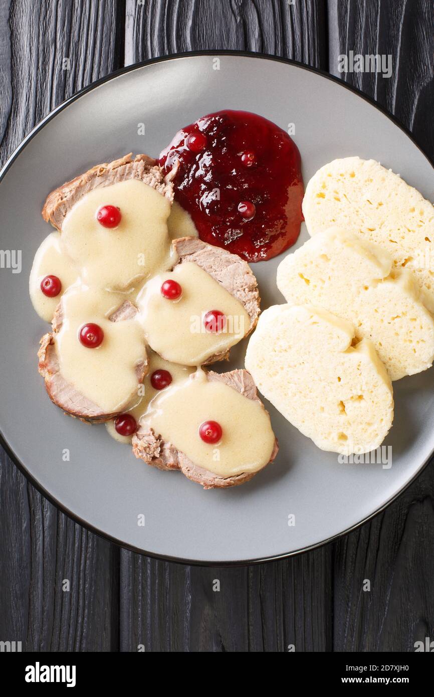Lo Svickova na smetane è un piatto tradizionale ceco preparato con filetto di manzo e verdure servite con marmellata di mirtilli rossi e gnocchi primo piano in una piastra su t Foto Stock