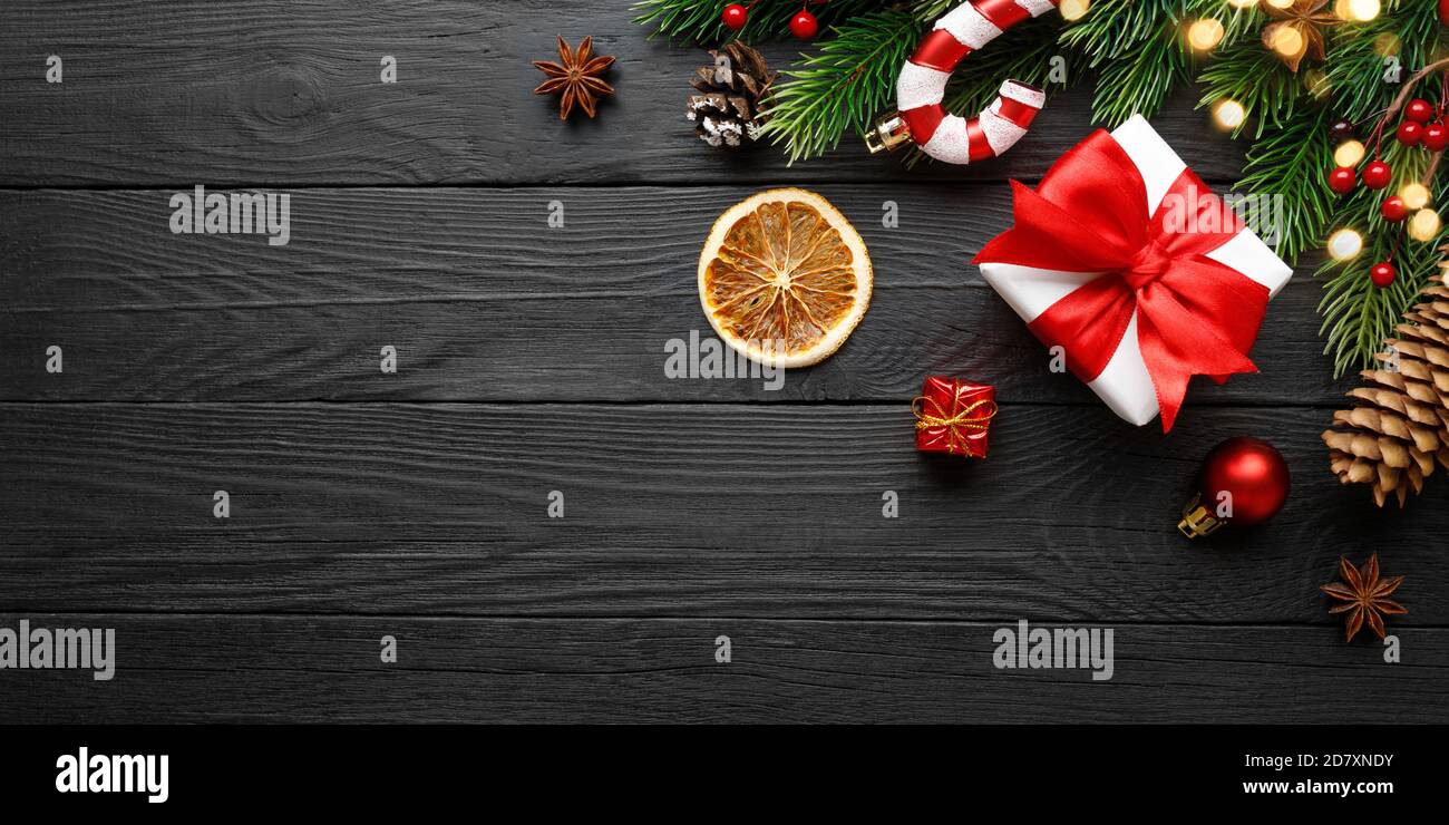Decorazioni natalizie con abete e regalo su legno nero sfondo Foto Stock
