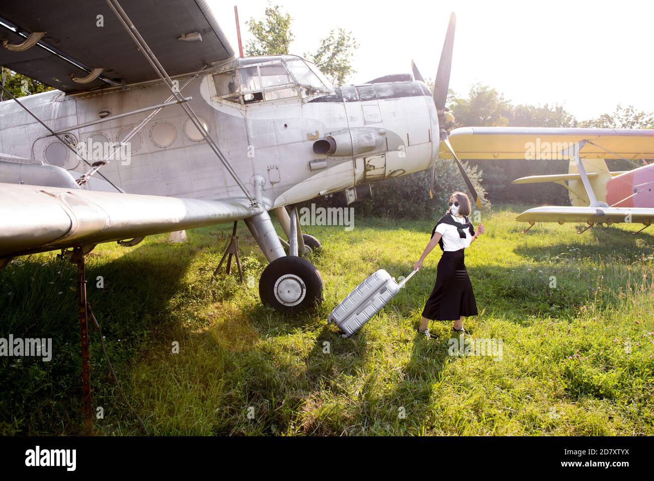 Giovane donna in una gonna nera che traina il suo bagaglio un campo d'aviazione d'epoca Foto Stock