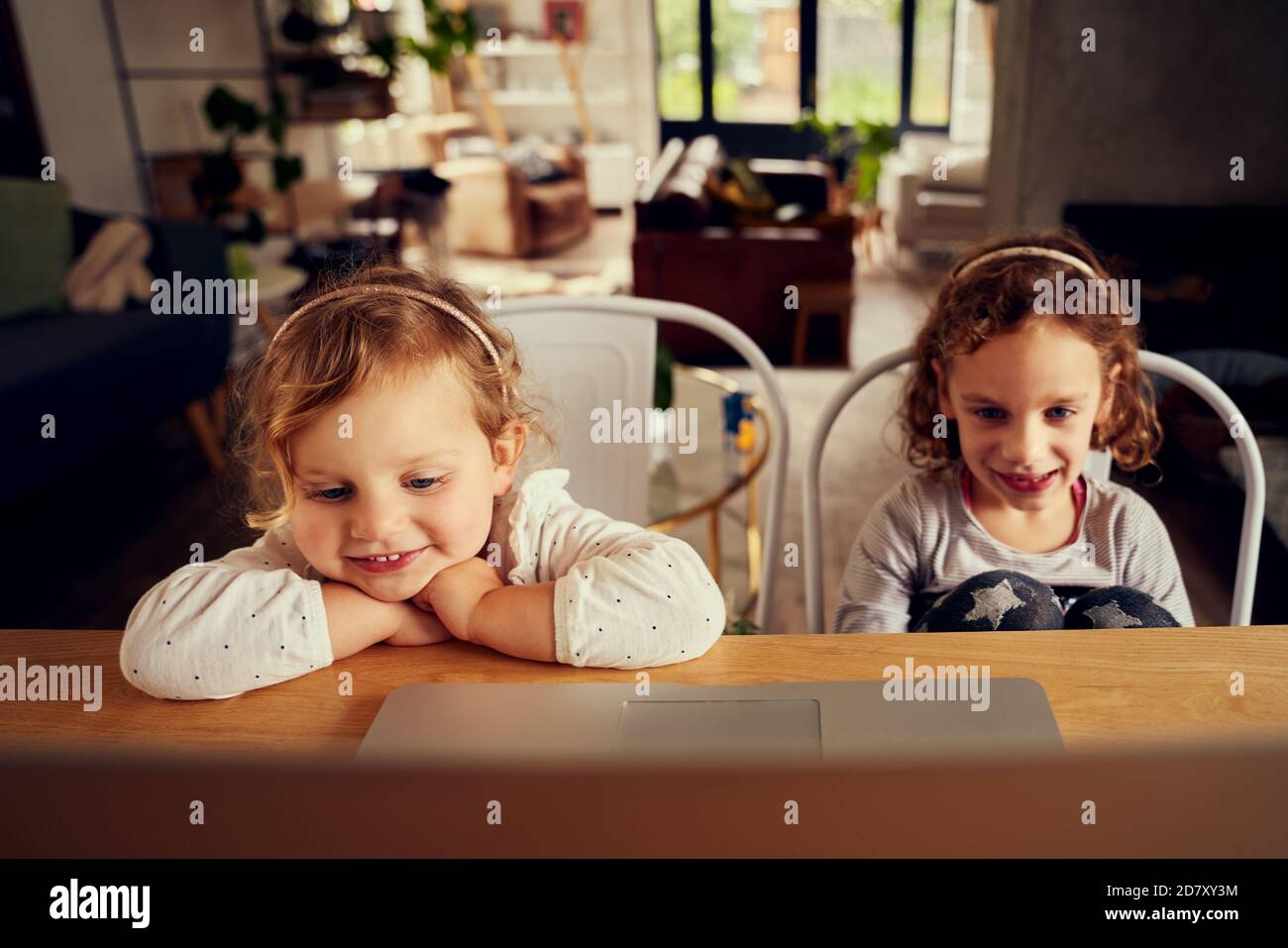 Adorabili piccole sorelle che guardano il video preferito dei cartoni animati su un computer portatile casa Foto Stock