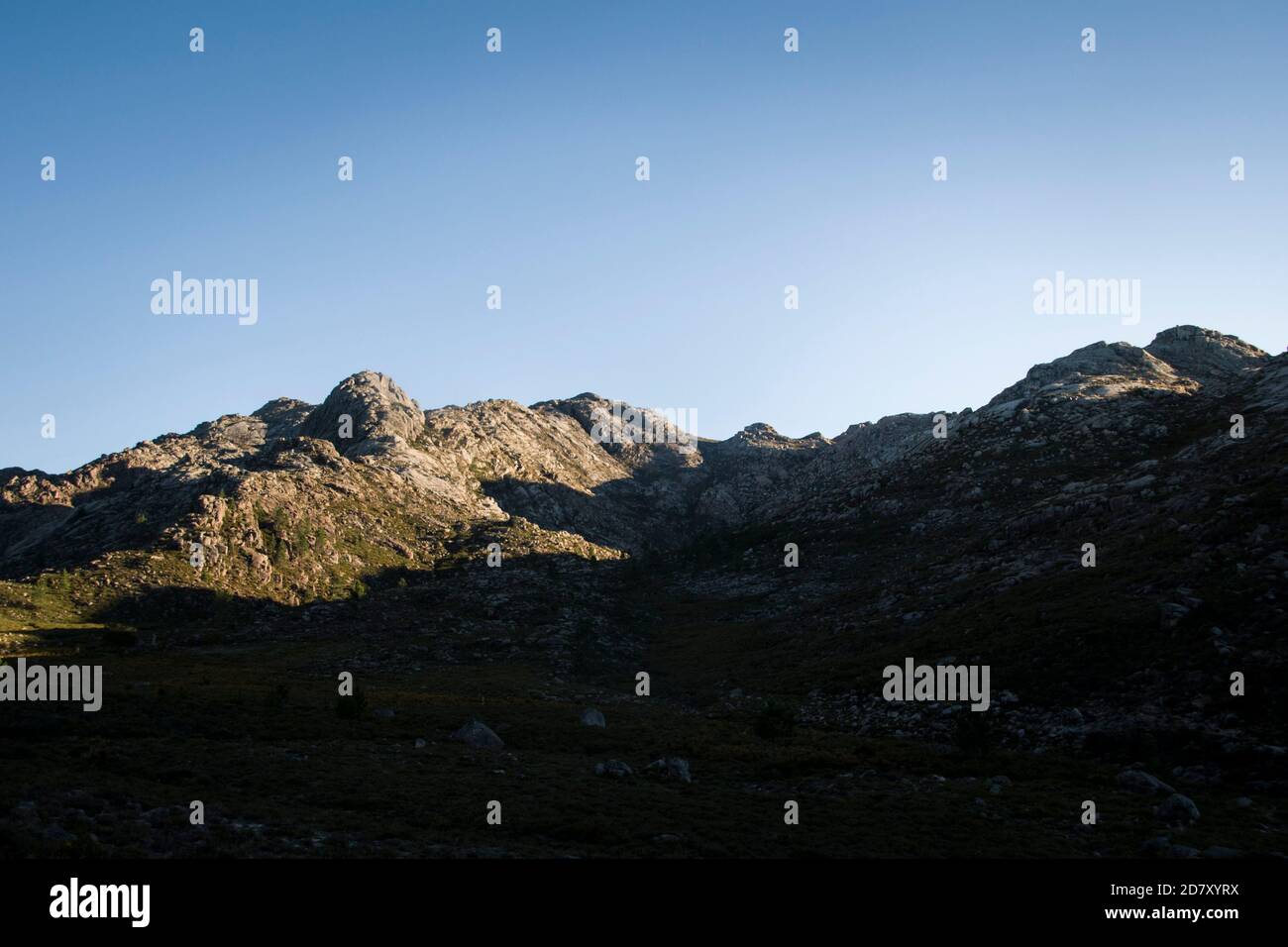 Paesaggio della valle di montagna che inizia ad essere illuminato dal primo luce al mattino mentre le ombre tornano indietro Foto Stock