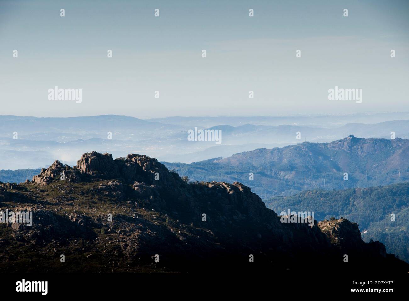 Le forme e le curve delle montagne svaniscono nell'orizzonte sottostante la nebbia mattutina Foto Stock