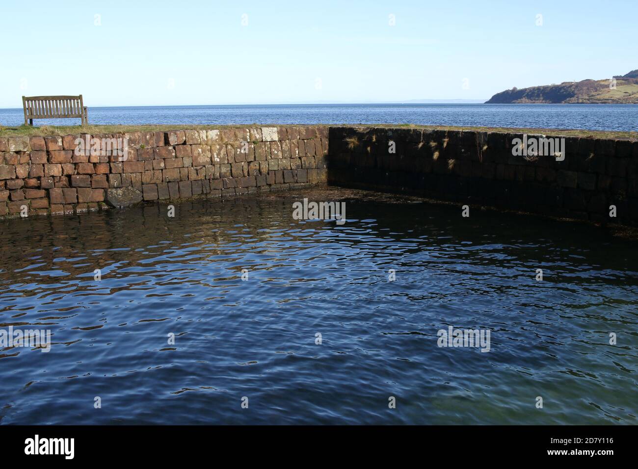 Muro con una panchina sulla costa vicino a Brodick, Isola di Arran, Sotland, Regno Unito Foto Stock