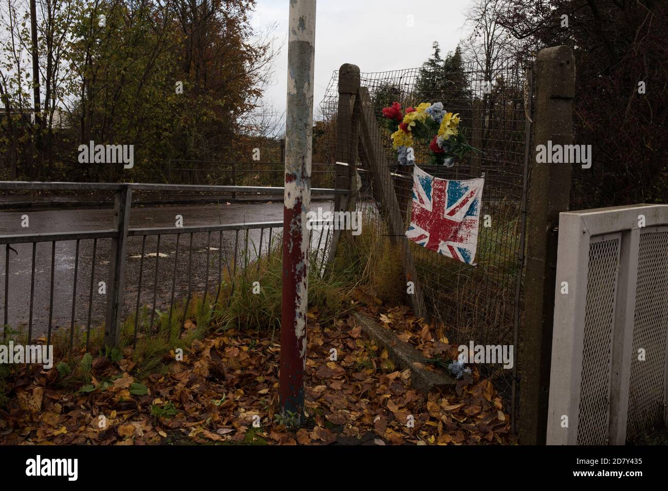 Bandiera dell'Unione e fiori di plastica in memoria del giovane, accanto alla stazione ferroviaria di Thornliebank, a Glasgow, Scozia, 26 ottobre 2020. Foto Stock