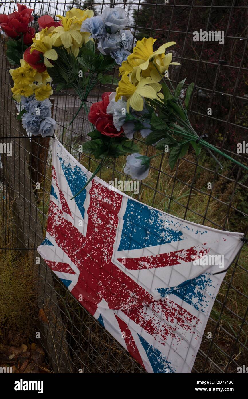 Bandiera dell'Unione e fiori di plastica in memoria del giovane, accanto alla stazione ferroviaria di Thornliebank, a Glasgow, Scozia, 26 ottobre 2020. Foto Stock