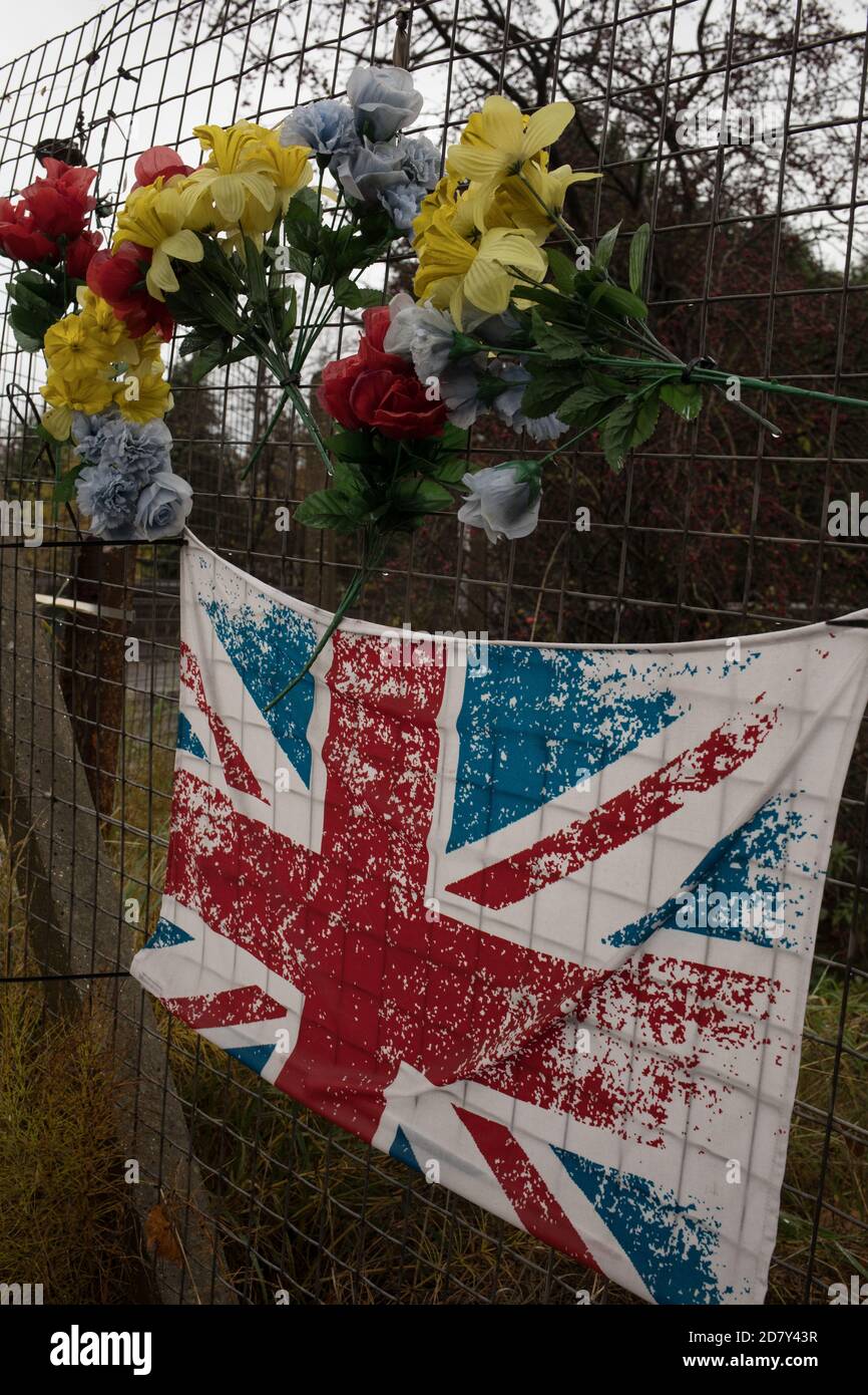 Bandiera dell'Unione e fiori di plastica in memoria del giovane, accanto alla stazione ferroviaria di Thornliebank, a Glasgow, Scozia, 26 ottobre 2020. Foto Stock