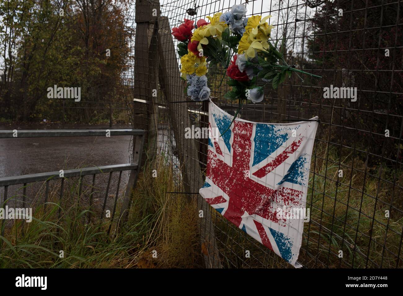 Bandiera dell'Unione e fiori di plastica in memoria del giovane, accanto alla stazione ferroviaria di Thornliebank, a Glasgow, Scozia, 26 ottobre 2020. Foto Stock