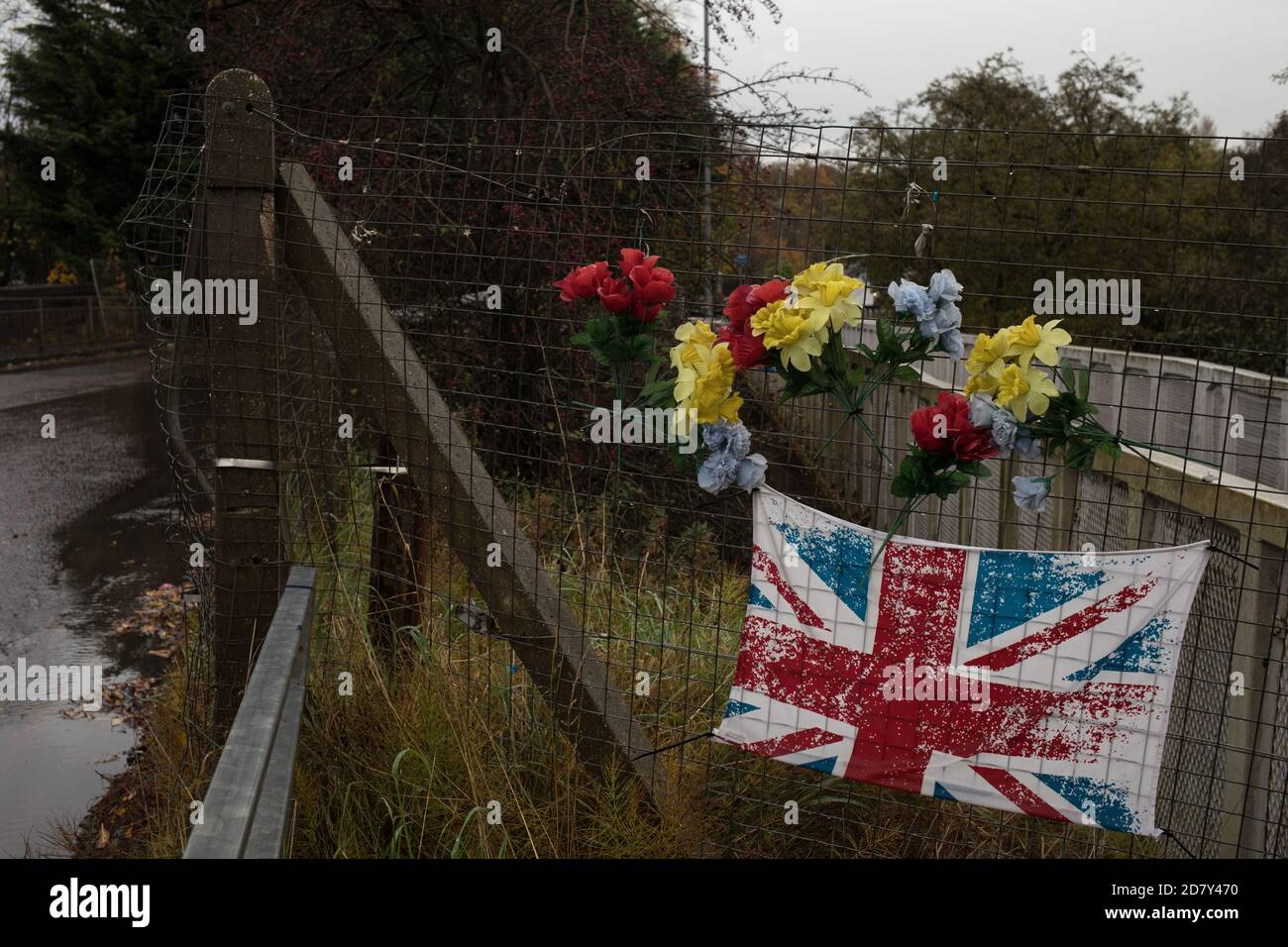 Bandiera dell'Unione e fiori di plastica in memoria del giovane, accanto alla stazione ferroviaria di Thornliebank, a Glasgow, Scozia, 26 ottobre 2020. Foto Stock