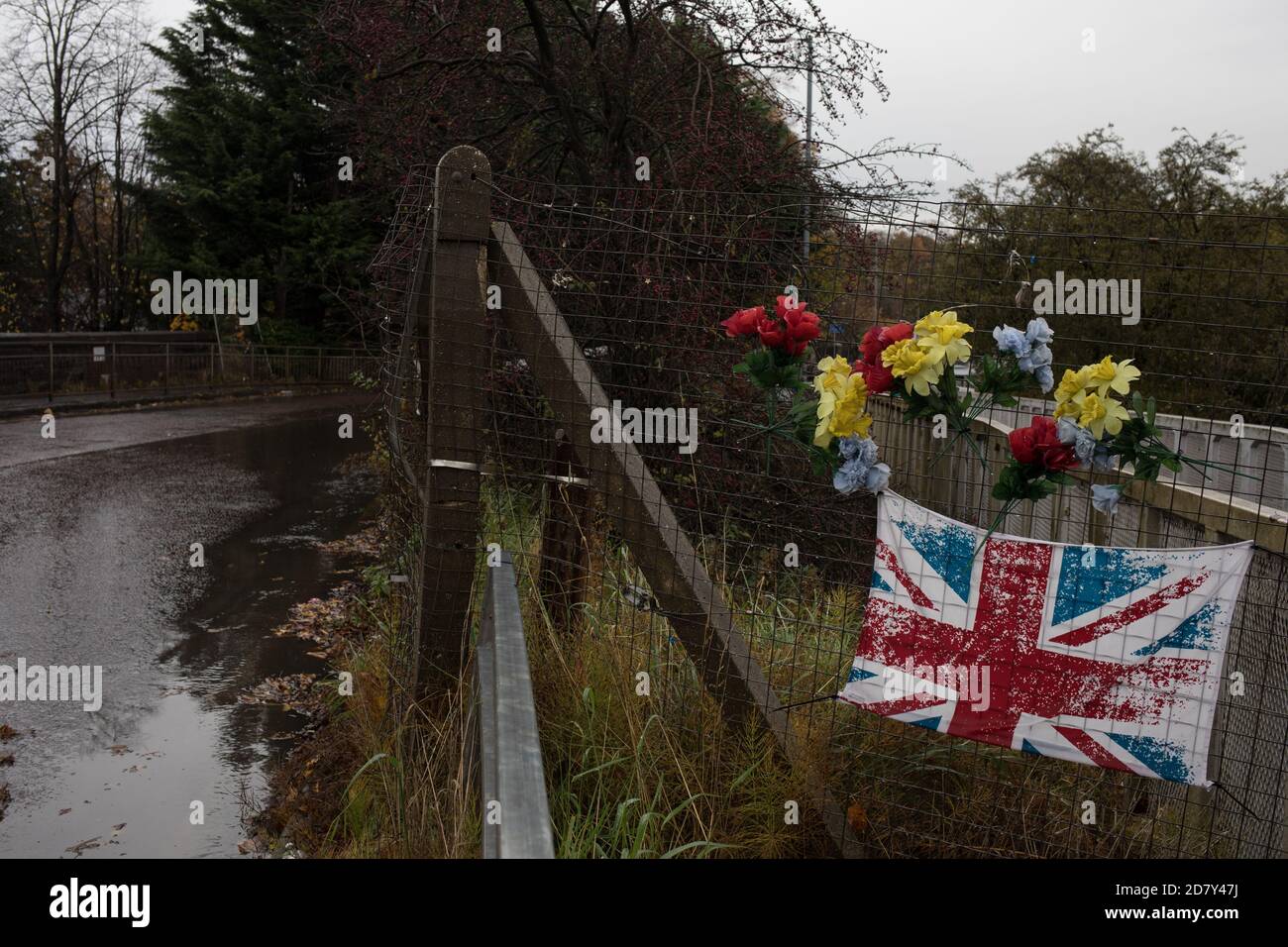 Bandiera dell'Unione e fiori di plastica in memoria del giovane, accanto alla stazione ferroviaria di Thornliebank, a Glasgow, Scozia, 26 ottobre 2020. Foto Stock