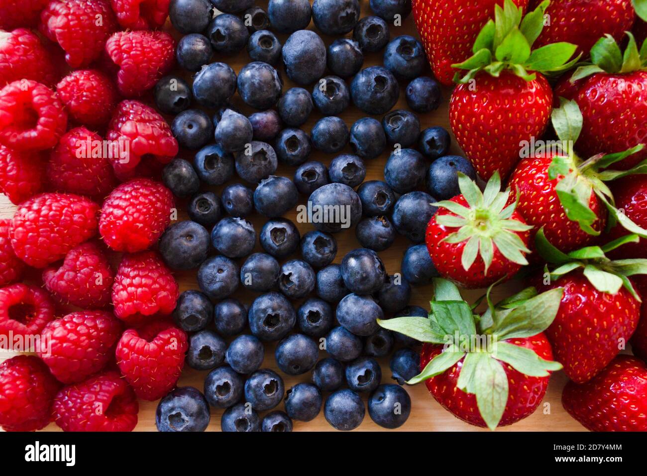 Fragola fresca, mirtillo e lampone. Frutta fresca di foresta colorata su sfondo di legno. Foto Stock