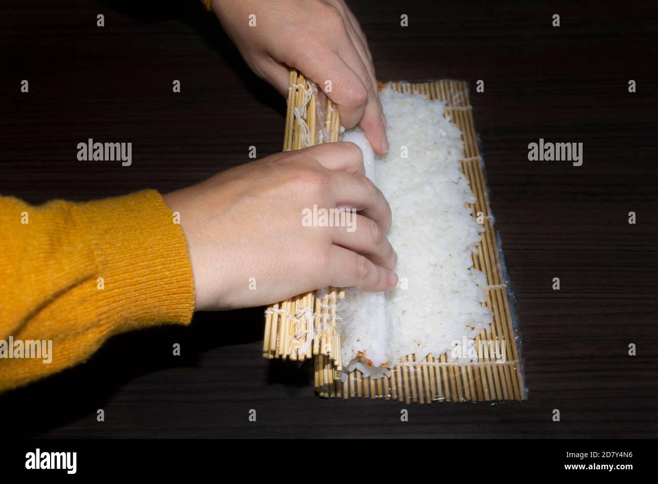 Le donne chef cucinano il sushi. Preparazione di un sushi roll. Concetto di cibo Giapponese. Foto Stock