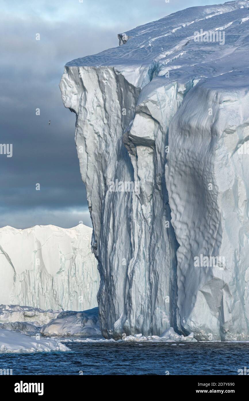 Iceberg drammatica scogliera verticale con spigoli di ghiaccio acuto raggiunge giù nell'acqua dell'Oceano Artico. Un colossale iceberg sta navigando nella Groenlandia di Disko Bay. Foto Stock