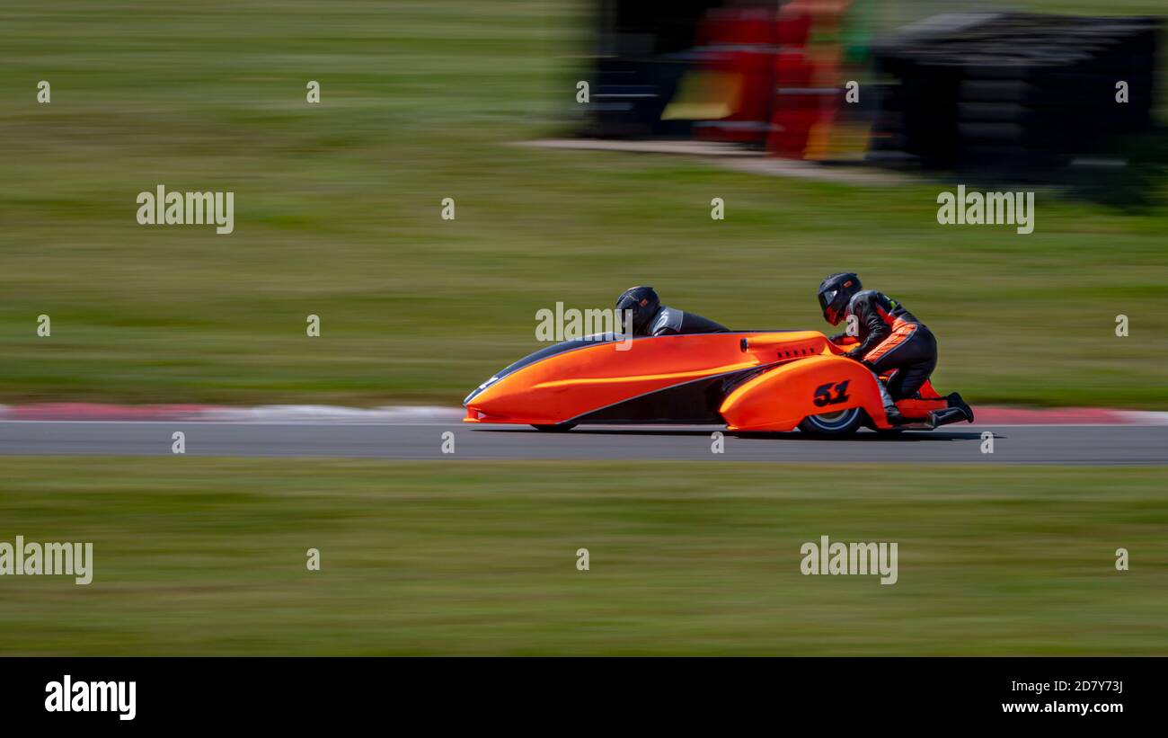 Una panoramica di un sidecar da corsa mentre si curva su una pista. Foto Stock
