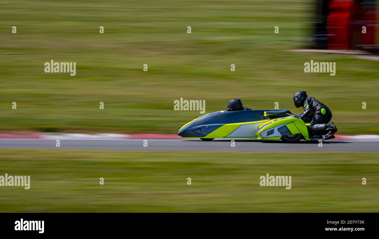 Una panoramica di un sidecar da corsa mentre si curva su una pista. Foto Stock