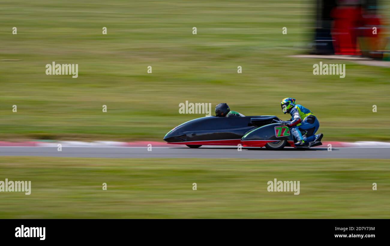 Una panoramica di un sidecar da corsa mentre si curva su una pista. Foto Stock