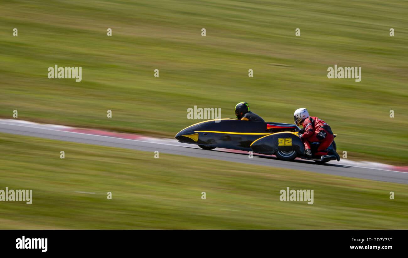 Una panoramica di un sidecar da corsa mentre si curva su una pista. Foto Stock