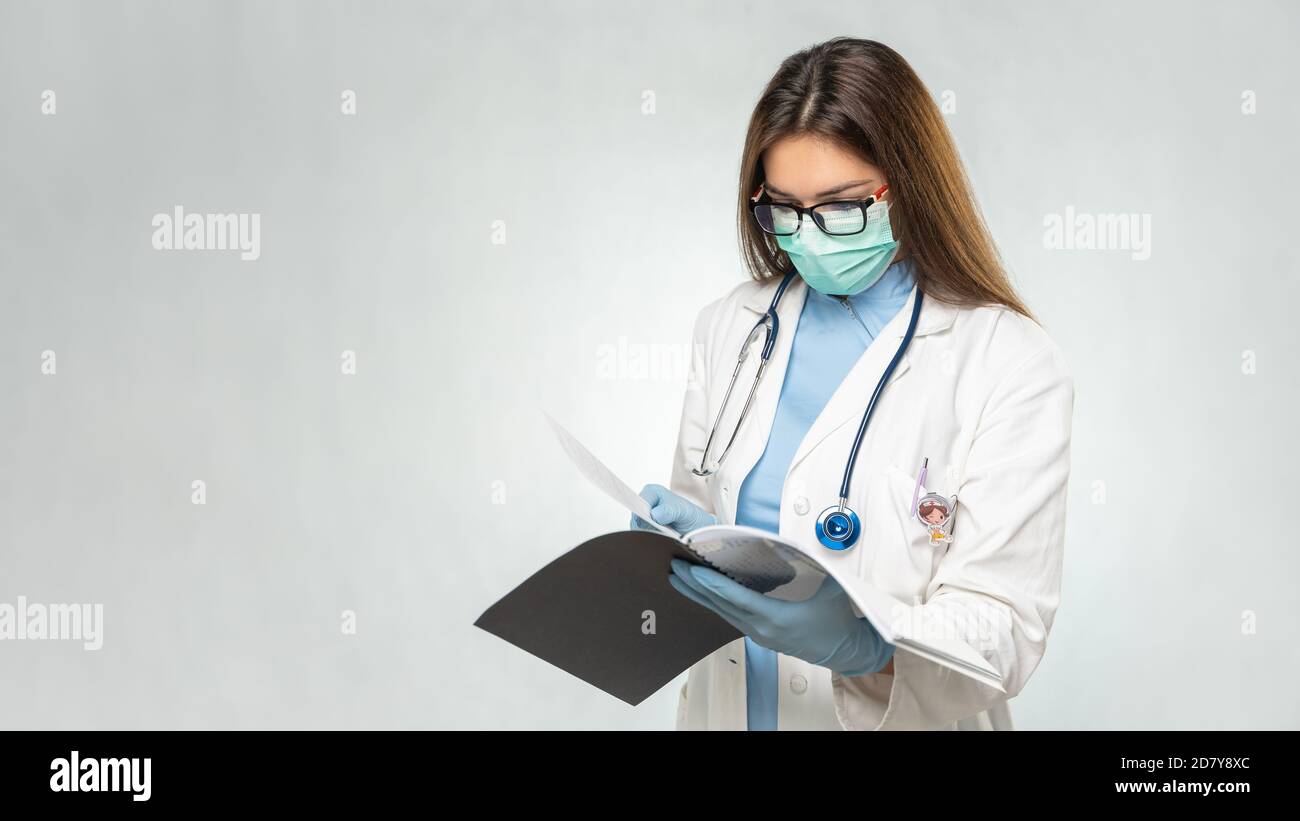 Giovane donna caucasica medico di lettura documenti. Cartella clinica. Foto Stock