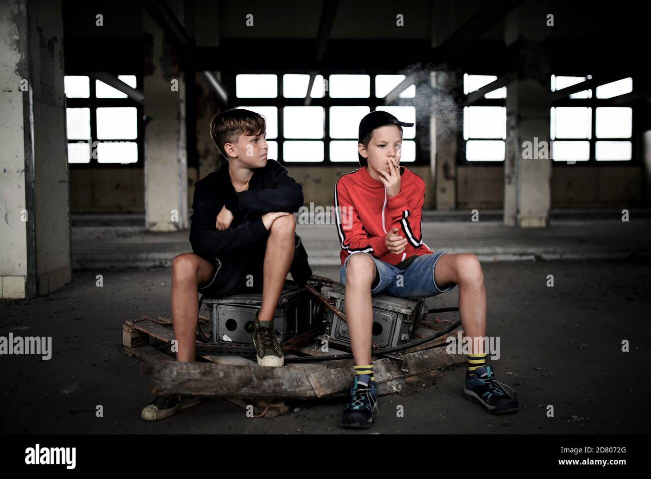Gruppo di ragazzi adolescenti all'interno di un edificio abbandonato, sigarette fumanti. Foto Stock